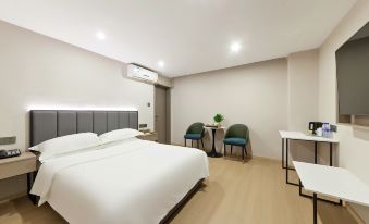 a modern hotel room with a large bed , white bedding , and two small tables with chairs at Diamond Hotel (Liancheng Guanzhishan Airport)