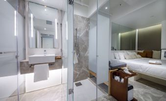 There is a bathroom with a shower, sink, and bed in the same room as another bedroom located opposite at The Charterhouse Causeway Bay