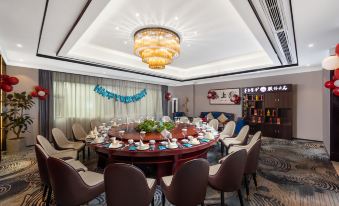 a large dining room with a round table surrounded by chairs , and a chandelier hanging from the ceiling at Mianyang Booking Hotel