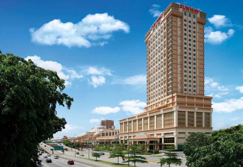 a large , modern building with a red - roofed structure is situated on a street near trees and other buildings at Sunway Lagoon Hotel , Formerly Sunway Clio Hotel
