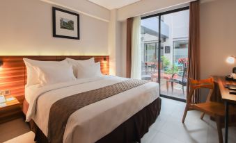 a clean and well - organized bedroom with a large bed , a chair , and a television at Swiss-Belinn Timika
