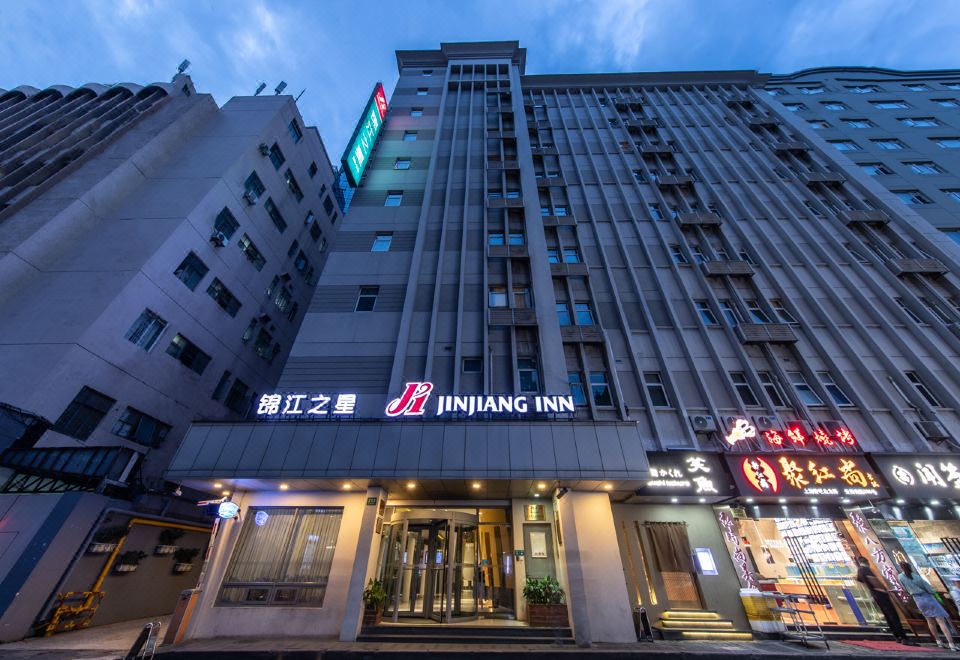 The hotel in an urban setting is surrounded by tall buildings, offering front and side views at Jinjiang Inn (Shanghai People's Square East Huaihai Road)