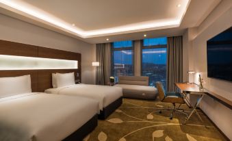The bedroom features large windows and double beds, with the same area rug as the other rooms at Novotel Shanghai Hongqiao