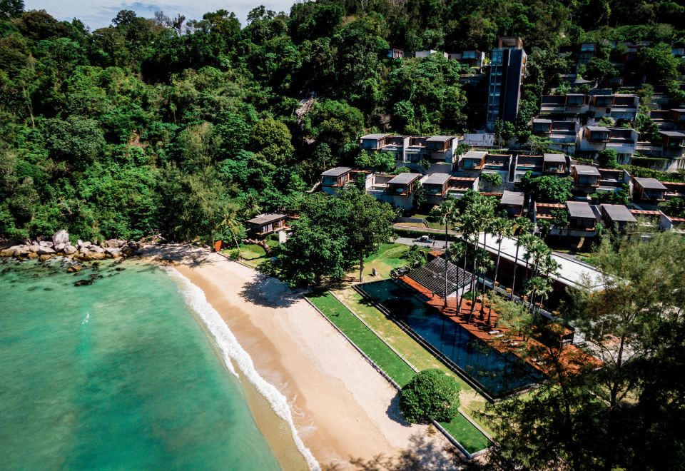 aerial view of a tropical resort surrounded by lush greenery , with a beach visible in the background at The Naka Phuket