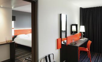 a modern hotel room with an open doorway , a bed , a desk , and a chair at Ibis Styles Caen Centre Gare
