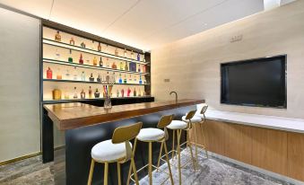 There is a centrally located bar with stools and chairs, adjacent to an open concept kitchen at X Hotel Taikoo Riaduo, Sanlitun, Beijing