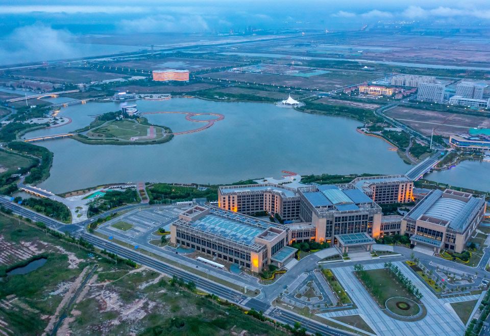 There is an aerial view of the city and lake with prominent buildings in the background, which includes a hotel at Continental Bridge Convention Centre Lianyungang China