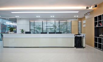 a modern office lobby with a white reception desk , multiple chairs , and a television mounted on the wall at Diamond Hotel (Liancheng Guanzhishan Airport)