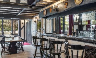 a dining room with wooden furniture , including chairs and a table , as well as a bar area at The Fox and Hounds Historic Hotel