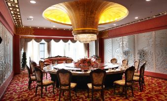 a large round dining table surrounded by ornate chairs in a room with red walls at Airport Hotel