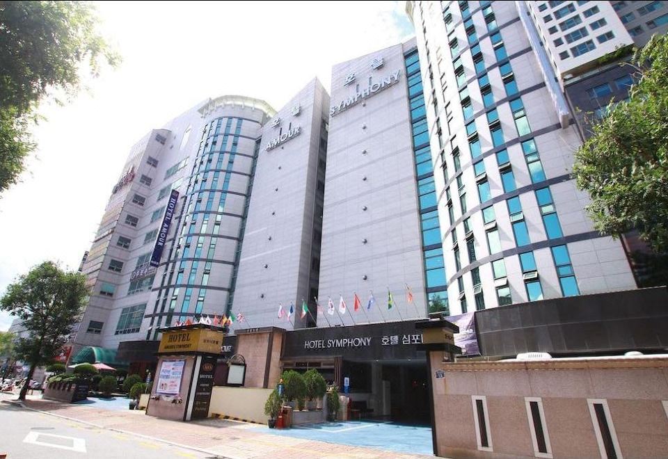 a tall , modern hotel building with multiple floors and balconies , situated on a busy street at Symphony Hotel