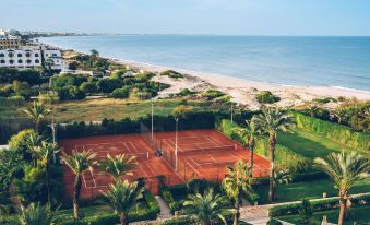 an aerial view of a tennis court surrounded by palm trees and a beach in the background at Iberostar Selection Royal El Mansour