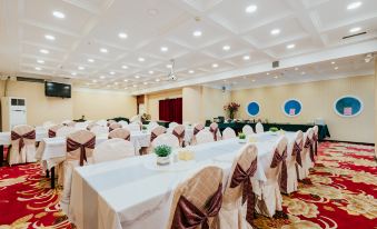 a large banquet hall filled with white tables and chairs , ready for a formal event at Victoria International Hotel