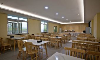 a large , empty dining room with wooden tables and chairs arranged for a group of people at Diamond Hotel (Liancheng Guanzhishan Airport)