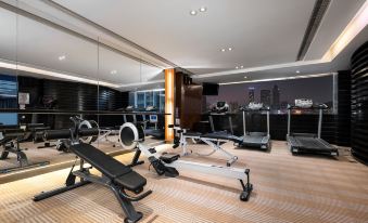 A spacious room with multiple exercise equipment and a centrally located indoor gym at Jianguo Hotel, Guangzhou
