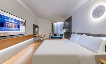 The modern bedroom features a large bed, a desk, and a wall-mounted flat-screen TV at Crystal Orange Hotel（Shanghai Hongqiao Gubei Road）