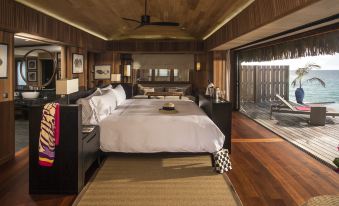 a large bedroom with a king - sized bed in the center , surrounded by hardwood floors and wooden walls at Conrad Bora Bora Nui