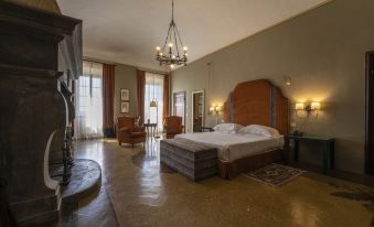 a spacious bedroom with a large bed , two chairs , and a fireplace in the background at Palazzo Leopoldo Dimora Storica & Spa