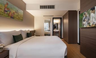 a large bed with white linens is in a room with wooden floors and brown walls at Oakwood Hotel and Residence Kuala Lumpur