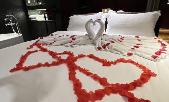 a bed is decorated with white sheets and a red rose - petal heart - shaped arrangement , creating a romantic atmosphere at M Hotels