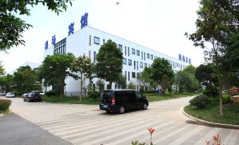 a black van is driving down a street in front of a large building with chinese characters on it at Airport Hotel