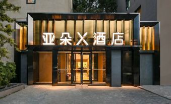 "At night, a hotel entrance is adorned with a sign that reads ""welcome"" and displays the hotel's logo" at X Hotel Taikoo Riaduo, Sanlitun, Beijing