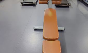 a gym with several treadmills and exercise equipment , including an orange bench press machine at Como Hotel