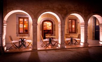 a cozy outdoor seating area with white chairs and tables , surrounded by an arched doorway at L'Hotel de Beaune