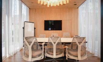 A spacious office with a large conference room featuring white chairs and a wooden table at HOMM Sukhumvit34 Bangkok - a brand of Banyan Group