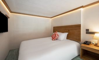 The luxury hotel features a modern bedroom with a white bed and an orange accent wall in the main room at Ramada Encore by Wyndham Shanghai Pudong Airport