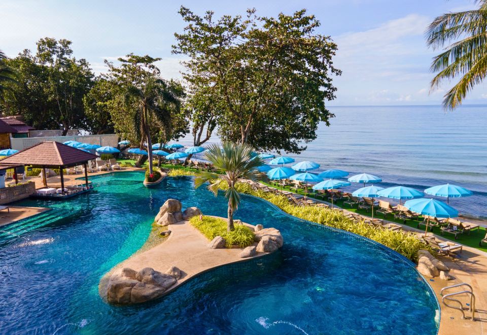 a beautiful resort with a large pool surrounded by umbrellas , palm trees , and ocean views at Kacha Resort & Spa, Koh Chang