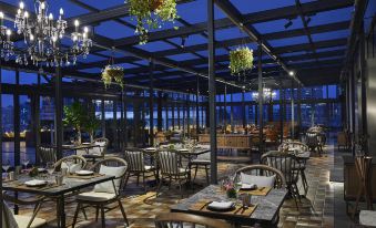 a restaurant with tables and chairs arranged in the center, all positioned to face an outdoor view at Conrad Shanghai