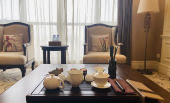a wooden table with a tea set , a vase , and a cup on it , set in front of two chairs and a window at Wellington Hotel