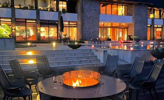 a modern building with a large fire pit surrounded by chairs and tables , creating a cozy outdoor dining experience at Sankara Hotel & Spa Yakushima