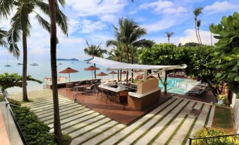 a luxurious outdoor dining area with umbrellas , lounge chairs , and a pool overlooking the ocean at Bandara Villas, Phuket