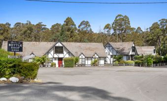 a row of white houses with red doors , situated in front of trees and under a clear blue sky at The Fox and Hounds Historic Hotel