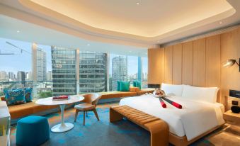 A bedroom with large windows and a centrally positioned bed, accompanied by two armchairs at W Shanghai - The Bund