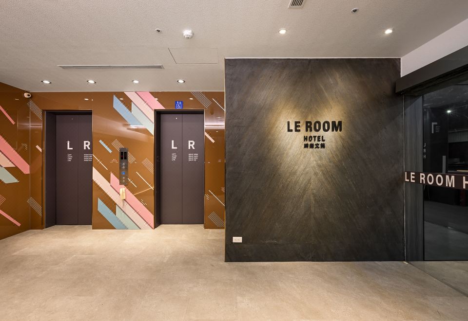 "a modern hotel lobby with a large wall mural and two elevators , one of which reads "" le room .""." at Le Room Hotel Taoyuan