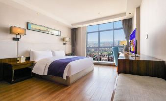 a large bedroom with a bed , couch , and tv , overlooking a cityscape through a window at Como Hotel