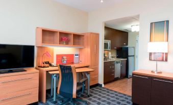 a small apartment with a dining table , chairs , and a kitchen in the background , as well as a desk and television in the foreground at TownePlace Suites by Marriott Champaign