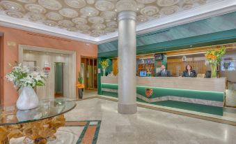 a hotel lobby with a reception desk , a man sitting at it , and a marble floor at Grand Hotel Adriatico