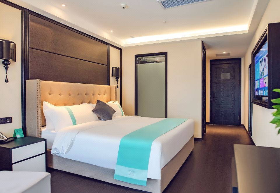 a large bed with white and blue linens is in a hotel room next to a door at Xuzhou Bo'an Hotel (University of Mining and Technology City Subway Station)
