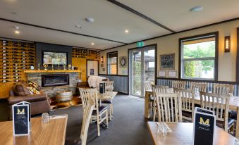 a dining room with wooden furniture and a fireplace , creating a cozy atmosphere in the space at Marsden Lake Resort Central Otago