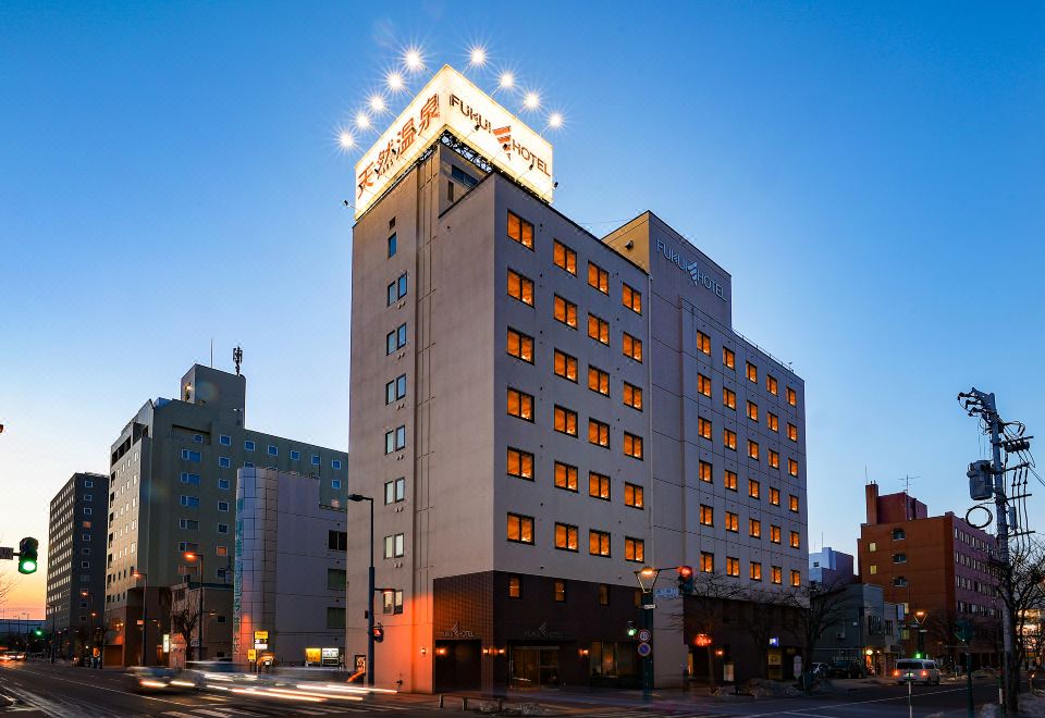 "a large building with the sign "" itemshop "" on top , illuminated at night , and surrounded by trees" at Fukui Hotel