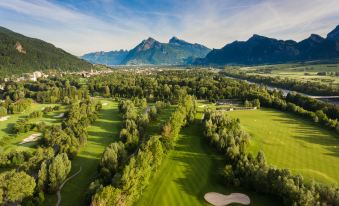 an aerial view of a golf course surrounded by trees , with mountains in the background at Grand Resort Bad Ragaz