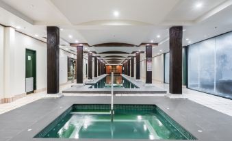 an indoor swimming pool with a long , narrow design and a glass wall in the background at Oaks Sydney Goldsbrough Suites