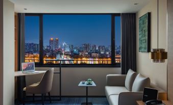 a hotel room with a large window overlooking the city at night , featuring comfortable seating and a desk at Guangzhou Hotel