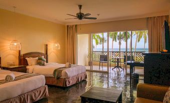 a hotel room with two beds , a living area , and a balcony overlooking the ocean at Palm Beach Resort & Spa