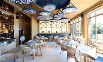 a modern restaurant with wooden tables , chairs , and blue lamps hanging from the ceiling , creating a cozy atmosphere at Bandara Villas, Phuket
