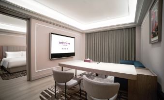 The conference room is equipped with a large table and chairs, and along the wall, there is an entertainment center featuring a television and a sound system for presentations and meetings at Mercure Guangzhou Beijing Road Pedestrian Street Hotel